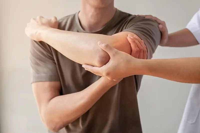 Kiné féminin manipulant le bras d'un patient